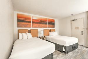 a hotel room with two beds and a painting on the wall at Hotel Carolina - Double Room 2 Full Beds in Hilton Head Island