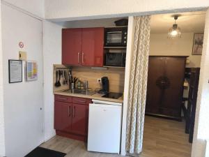 a kitchen with red cabinets and a white refrigerator at Les marmottes in Aragnouet