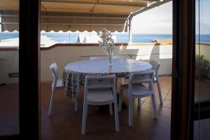 a table and chairs sitting on a balcony with the ocean at Attico Sul Mare In Centro in Capo dʼOrlando