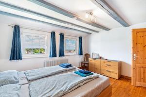 two beds in a bedroom with blue curtains at Ferienhaus St Georg Stube in Grömbach