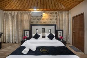 una habitación con una cama grande con sábanas y almohadas blancas en Apple Tree Villa By Exotic Stays, en Shimla