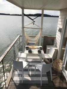 a porch with a table and chairs on a boat at Hausboot Koje Kaete mit großem Sonnendeck in Schleswig in Schleswig +8 photos