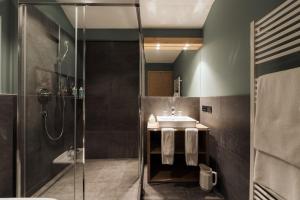 une salle de bain avec douche et lavabo dans l'établissement Berghotel Ladinia, à Corvara in Badia