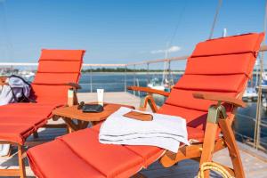 two red chairs and a table on a boat at Hausboot Smaragd Heiligenhafen in Heiligenhafen