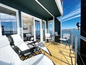 a balcony with white chairs and a table and water at STERN V Hausboot Heiligenhafen in Heiligenhafen