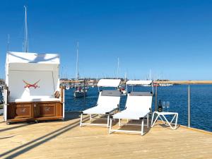 two chairs and a table on a dock near the water at STERN V Hausboot Heiligenhafen in Heiligenhafen +7 photos