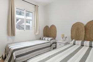 zwei Betten in einem weißen Zimmer mit Fenster in der Unterkunft Apartamento Perez Zara 3 in Conil de la Frontera