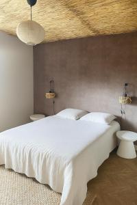 a bedroom with a large white bed with two tables at Gîte Minimalist in Commentry