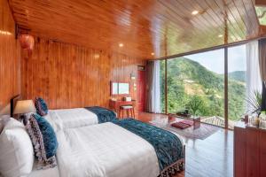 a bedroom with two beds and a large window at Heaven Gate O Quy Ho Hotel Sapa in Lao Cai
