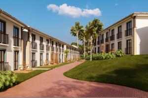 a walkway through a courtyard with palm trees and grass at QSB - Quinta Santa Bárbara in Pirenópolis