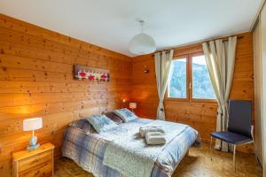a bedroom with a bed with wooden walls and a window at Meublé spacieux - chaîne des Aravis in Saint-Jean-de-Sixt