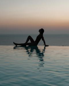 a woman sitting on a surfboard in the water at Creta Blue Boutique Hotel in Hersonissos