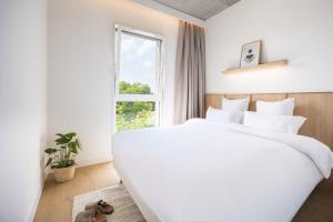 a white bedroom with a large bed and a window at BABEL COMMUNITY Hôtel Saint-Quentin-en-Yvelines in Montigny-le-Bretonneux +50 photos