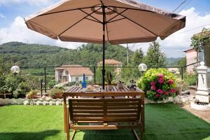 a wooden table with an umbrella in a yard at La Casa di Giosy in Cairo Montenotte