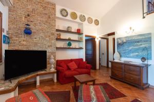 a living room with a red couch and a tv at Amazing sunset with swimming pool in Custonaci