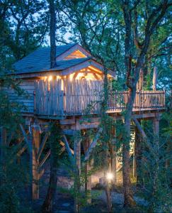 a tree house with a deck in the trees at Domaine de Pech et Lafon Cabanes avec SPA privatif dans les arbres in Clairac