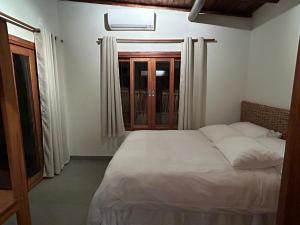 Un dormitorio con una cama blanca y una ventana. en Corumbau Bangalôs, en Prado