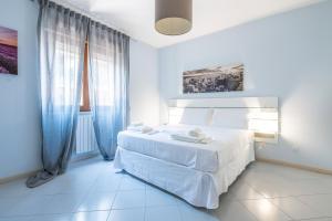 a white bedroom with a white bed with blue curtains at P012 Apartment in Cagliari