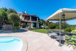 a patio with an umbrella and a swimming pool at Villa Cala Bitta in Arzachena