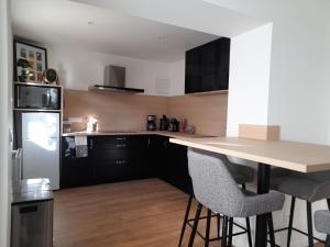 a kitchen with black cabinets and a counter with bar stools at Au nid de cigo in Sigolsheim