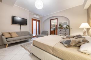 a bedroom with a bed and a couch and a tv at Suite Home Simius in Villasimius