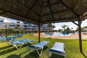 Un grupo de tumbonas y una piscina. en La Terraza del Mar, en Manilva
