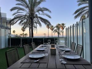 a wooden table with plates and wine glasses on a balcony at Residencial Mar de Denia 2 in Denia