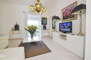 un salon avec une télévision et un vase de fleurs dans l'établissement Tres Pins, à Artà