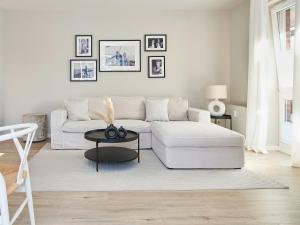 a white living room with a white couch and a table at Techts Strandhaus in Timmendorfer Strand