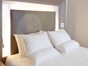 a bed with two white pillows in a room at Novotel Coventry in Coventry +105 photos