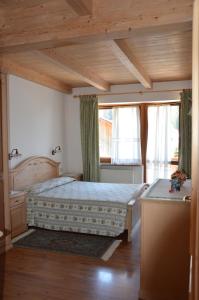 a bedroom with a bed and a wooden ceiling at Garní Ladinia in Pescul