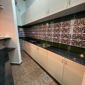 a kitchen with a sink and a tile wall at Qurum Heights Hotel in Muscat +15 photos