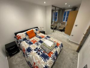 a bedroom with a bed with an orange and blue blanket at WBC Modern Ensuite room Wednesbury R3 in Bilston +11 photos