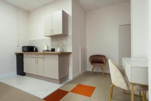 eine Küche mit weißen Schränken, einem Tisch und einem Stuhl in der Unterkunft Moon Apartments Wrocław in Breslau