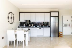 a kitchen with white cabinets and a table and chairs at The Blue Tide - 1 Bedroom Apartment - All Bills Included in Alanya