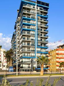 a tall building with a palm tree in front of it at The Blue Tide - 1 Bedroom Apartment - All Bills Included in Alanya