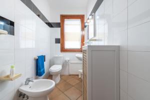 a white bathroom with a toilet and a sink at Maya in Villasimius +16 photos