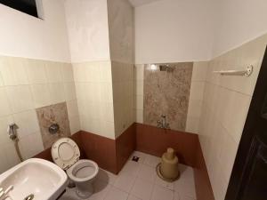 a bathroom with a toilet and a sink at Downtown in Manipala +4 photos