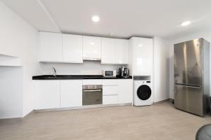 トレ・デ・ベナガルボンにあるDreamy Beach Duplexの白いキャビネットとステンレス製の冷蔵庫を備えたキッチン