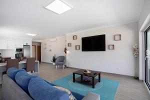 a living room with a couch and a tv on a wall at Villa Flor Rosa Piscina e Jacuzzi in Salir de Matos