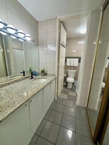 a bathroom with a sink and a toilet and a mirror at Isla Verde Serenity by the Sea in San Juan