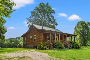 a log cabin with a porch on a grass field at Heavenly Hideaway - near Red River Gorge KY in Beattyville
