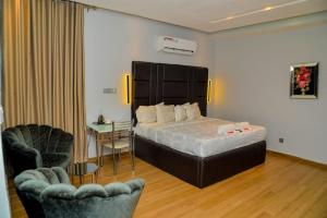 a bedroom with a bed and a desk and two chairs at Triple Tee Luxury Hotel & Service Apartments Surulere in Lagos