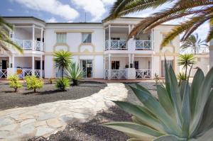 a large white building with palm trees in the foreground at Casa Verdemar in Corralejo
