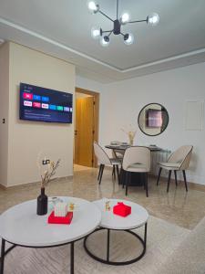 a living room with tables and chairs and a tv at Appartement Cocooning de Sousse in Hammam Sousse