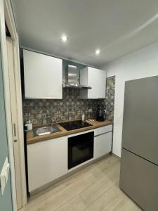 a kitchen with white cabinets and a sink and a refrigerator at AparthouseRisorgimento CANAPA in Frattamaggiore