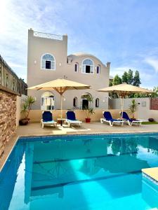 a villa with a swimming pool in front of a house at Royal Home Dome Style - Ground Floor Apartment in Jazīrat al ‘Awwāmīyah