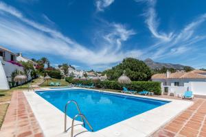 una piscina en una villa con una montaña en el fondo en Townhouse El Naranjal, en Marbella