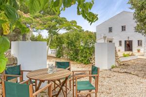 an outdoor table and chairs in front of a house at Finca Biniatzau in Alaior
