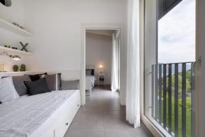 een witte slaapkamer met een bed en een balkon bij Ca’ Scaì Agrifugium Elià in Tignale